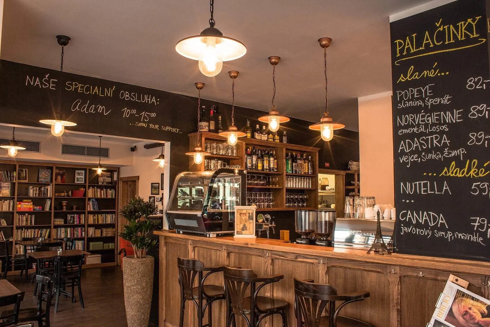 Bar s rozsvícenými měděnými lampami a knihovna